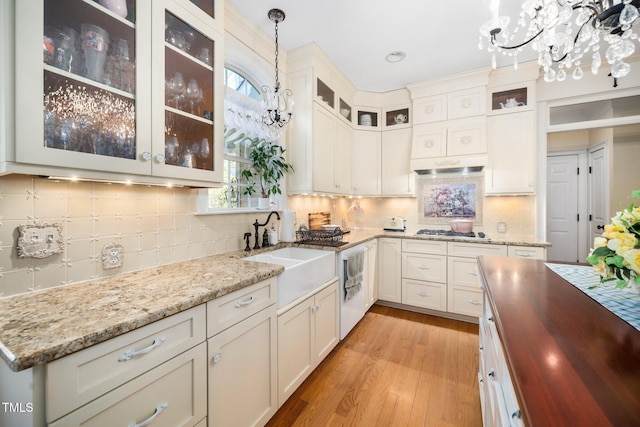 kitchen with a chandelier, light wood-type flooring, decorative light fixtures, and a sink