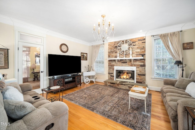 living area featuring crown molding, an inviting chandelier, a stone fireplace, wood finished floors, and baseboards