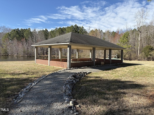 view of property's community with a lawn, a view of trees, and a gazebo