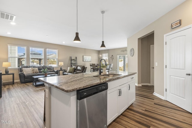 kitchen with a sink, visible vents, white cabinets, stainless steel dishwasher, and dark stone countertops