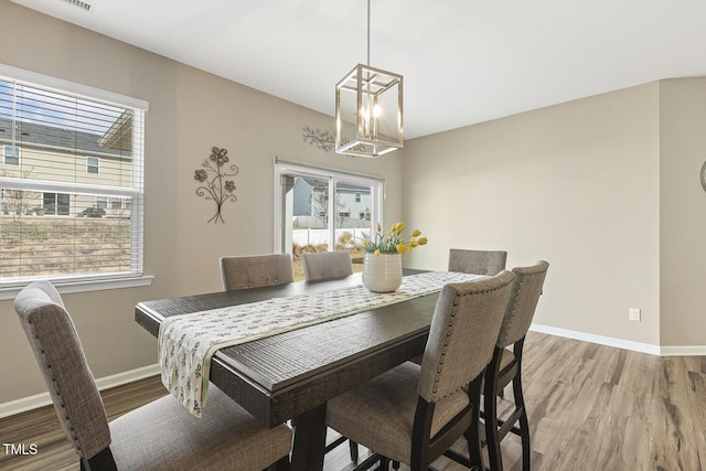 dining room with light wood-type flooring, baseboards, and an inviting chandelier