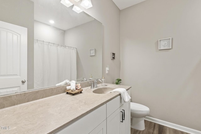 bathroom with baseboards, vanity, toilet, and wood finished floors