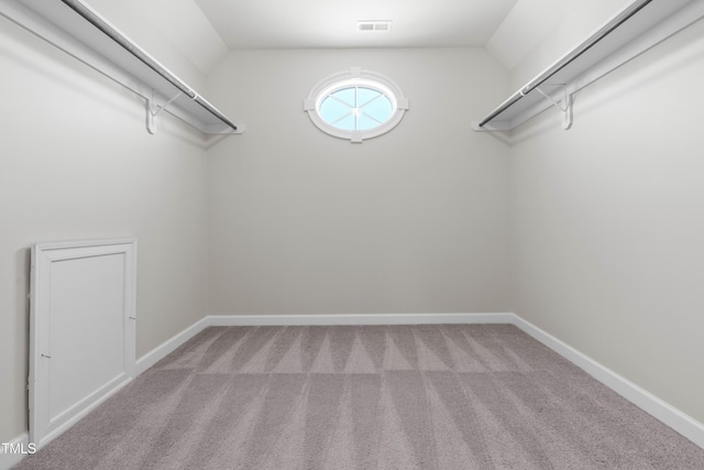 walk in closet with vaulted ceiling, visible vents, and light colored carpet