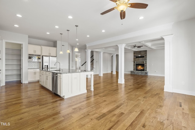 kitchen with pendant lighting, a center island with sink, appliances with stainless steel finishes, open floor plan, and white cabinetry