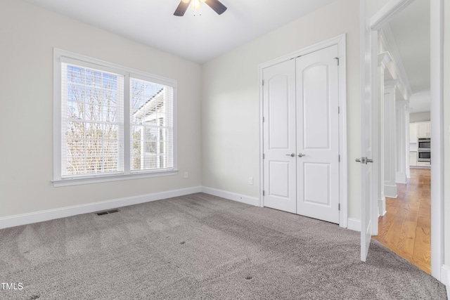 unfurnished bedroom with baseboards, visible vents, a ceiling fan, carpet floors, and a closet