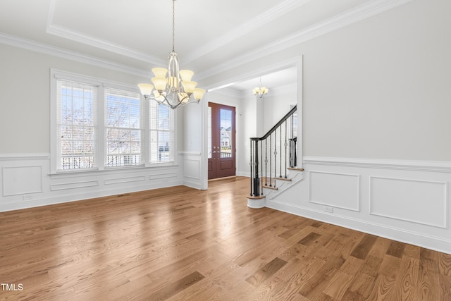 entryway featuring wood finished floors, visible vents, ornamental molding, stairway, and an inviting chandelier