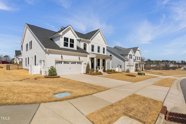 view of front of home with board and batten siding, fence, roof with shingles, a garage, and driveway