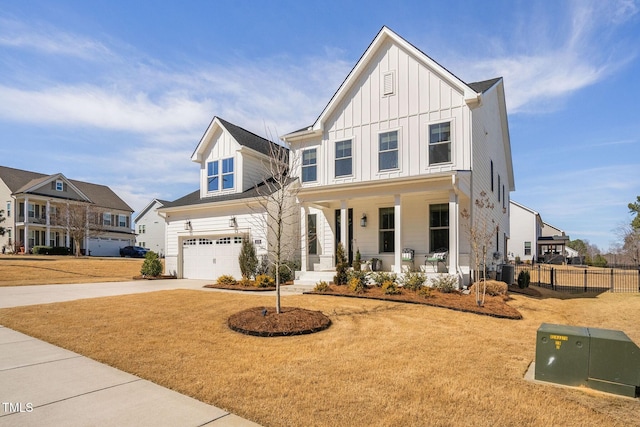 modern farmhouse style home with fence, covered porch, concrete driveway, a front lawn, and board and batten siding