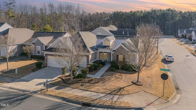 view of front of home with solar panels, concrete driveway, a standing seam roof, metal roof, and stone siding