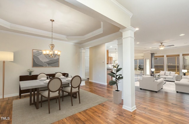 dining area featuring baseboards, ornamental molding, wood finished floors, ornate columns, and ceiling fan with notable chandelier