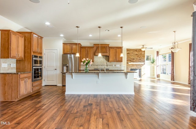 kitchen featuring brown cabinets, dark wood-style flooring, a kitchen breakfast bar, stainless steel appliances, and crown molding