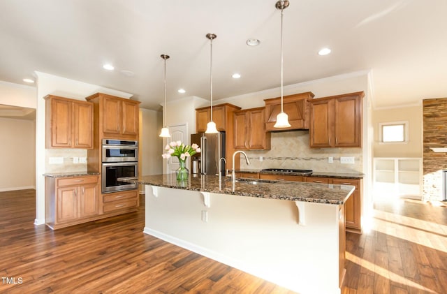 kitchen with appliances with stainless steel finishes, brown cabinets, a sink, and a breakfast bar area