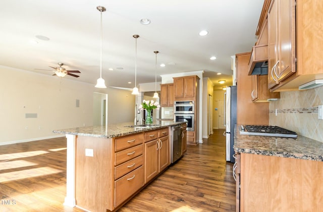 kitchen featuring stainless steel appliances, wood finished floors, a sink, and a center island with sink