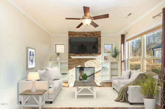 living room featuring a fireplace, crown molding, visible vents, and wood finished floors