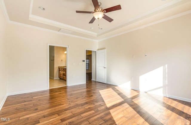 unfurnished bedroom featuring ornamental molding, hardwood / wood-style floors, a raised ceiling, and baseboards