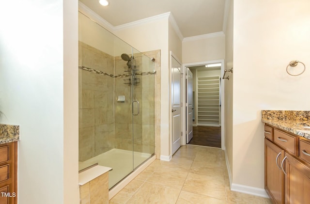 full bathroom with a stall shower, baseboards, a spacious closet, crown molding, and vanity