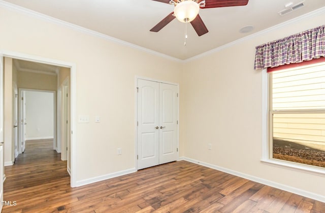 unfurnished bedroom with baseboards, crown molding, visible vents, and wood finished floors