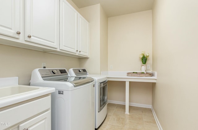 laundry room featuring separate washer and dryer, cabinet space, and baseboards