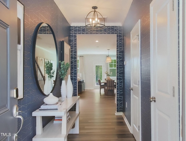 entryway featuring wood-type flooring, ornamental molding, and a notable chandelier