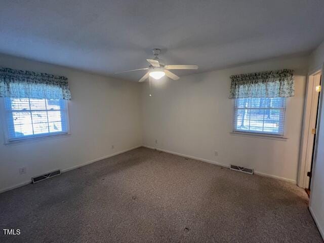 carpeted empty room with ceiling fan and plenty of natural light