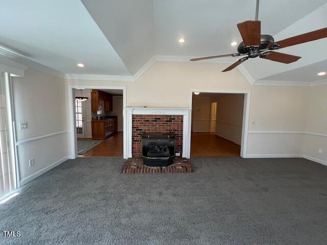 unfurnished living room with crown molding, vaulted ceiling, ceiling fan, and dark carpet