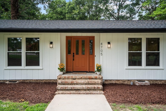 entrance to property featuring roof with shingles