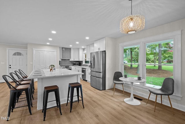 kitchen with light wood-type flooring, white cabinetry, tasteful backsplash, and appliances with stainless steel finishes