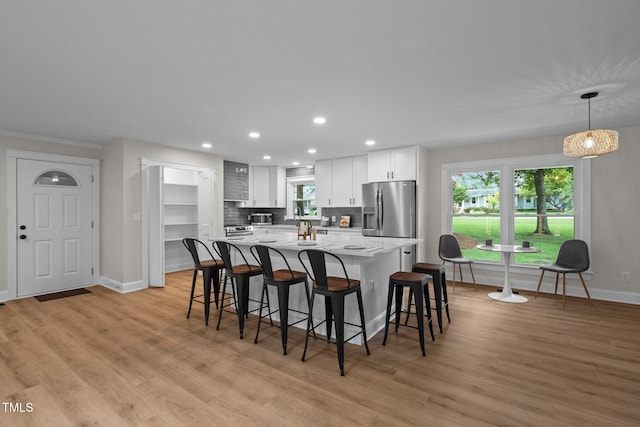 kitchen featuring stainless steel fridge, a kitchen bar, white cabinetry, and a center island