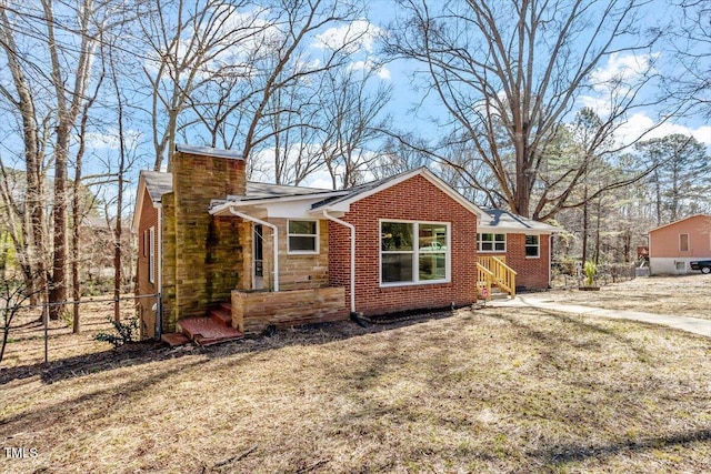 view of front facade with a chimney, fence, and brick siding