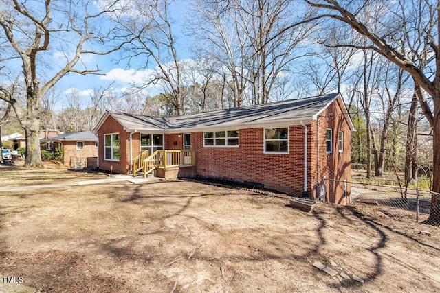 ranch-style home with brick siding, fence, and dirt driveway