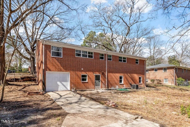 view of front of home featuring brick siding, driveway, an attached garage, and central air condition unit