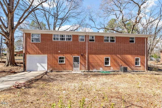 view of front of property with a garage, concrete driveway, brick siding, and cooling unit