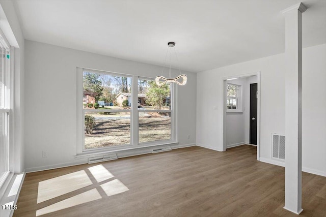 unfurnished dining area featuring a wealth of natural light, wood finished floors, and visible vents