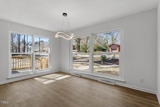 unfurnished dining area featuring wood finished floors, visible vents, and baseboards