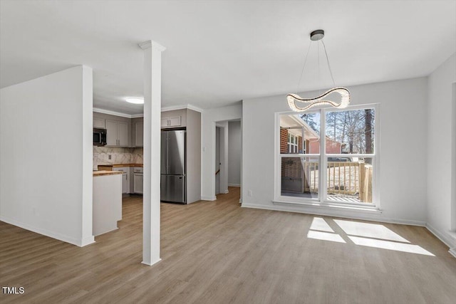 unfurnished dining area featuring baseboards and light wood-style floors