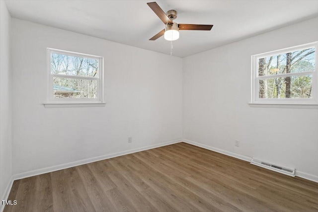 spare room with a healthy amount of sunlight, visible vents, baseboards, and wood finished floors