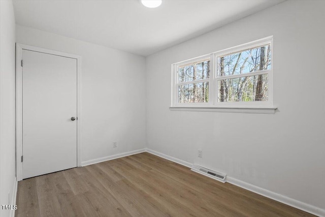 unfurnished bedroom featuring baseboards, visible vents, and wood finished floors