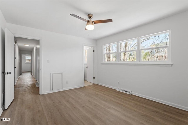 unfurnished bedroom with a ceiling fan, baseboards, visible vents, and wood finished floors