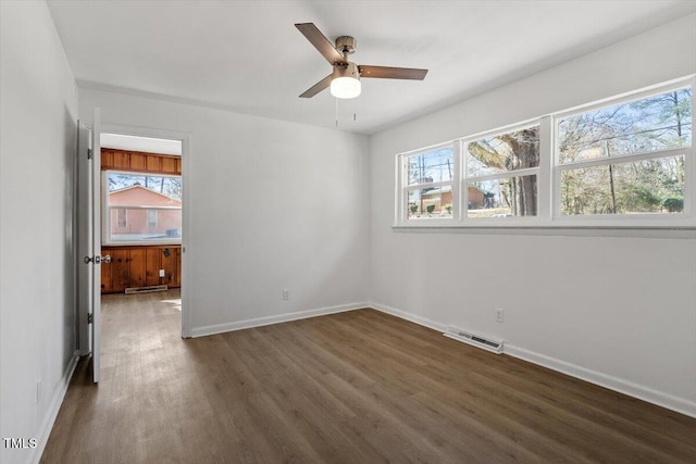 spare room with visible vents, plenty of natural light, baseboards, and wood finished floors