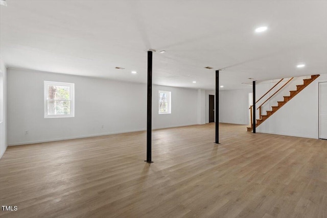 below grade area with a healthy amount of sunlight, light wood-style floors, and stairs