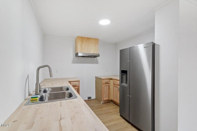 kitchen featuring crown molding, light countertops, stainless steel fridge, and a sink