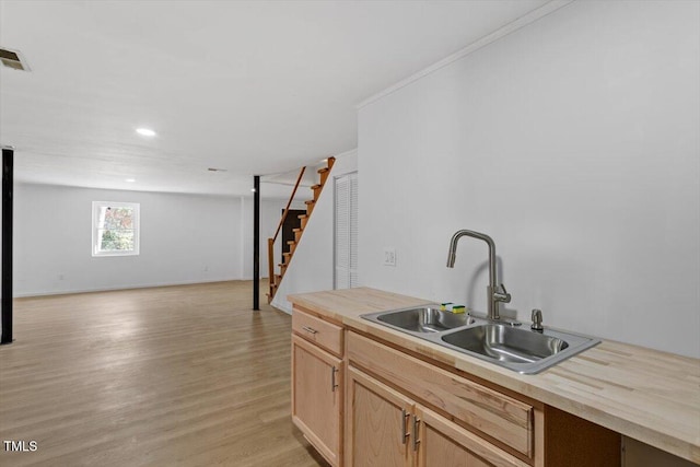 kitchen featuring visible vents, open floor plan, light wood-style floors, light brown cabinets, and a sink