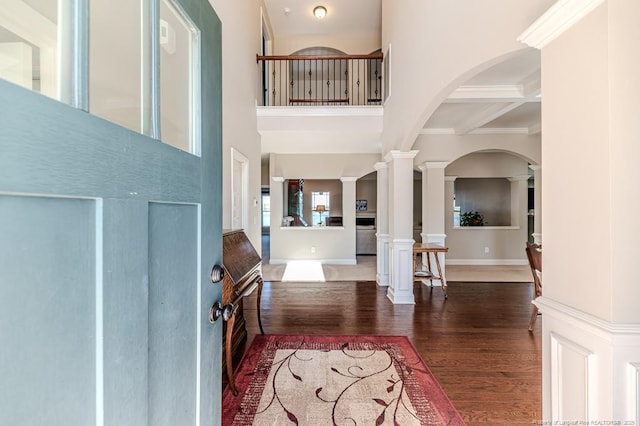 foyer with ornate columns, beamed ceiling, dark hardwood / wood-style flooring, a high ceiling, and coffered ceiling