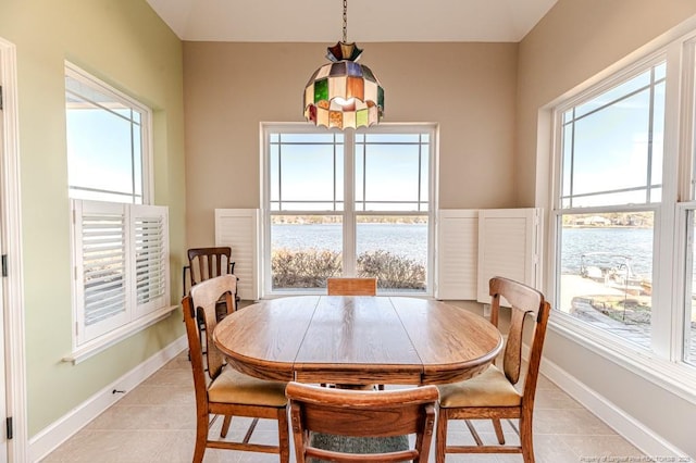 dining area featuring a water view and light tile patterned floors