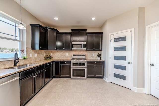 kitchen featuring sink, decorative light fixtures, stainless steel appliances, and light stone countertops