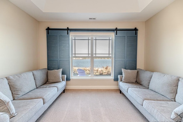 living room featuring a water view, a raised ceiling, a barn door, and carpet floors