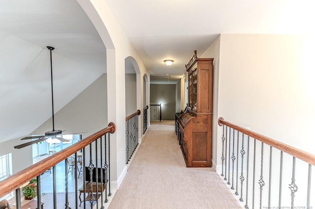 hall with lofted ceiling and light colored carpet