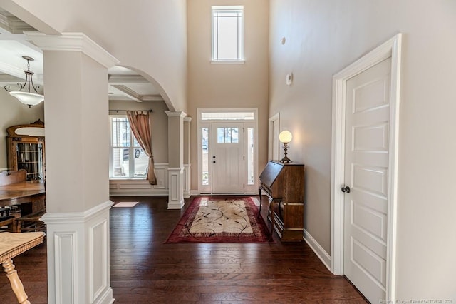 foyer entrance featuring ornate columns, dark hardwood / wood-style floors, and beamed ceiling