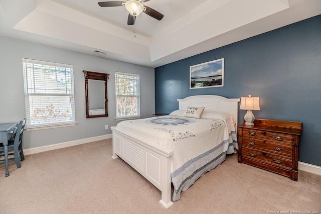 bedroom with light carpet, ceiling fan, and a tray ceiling