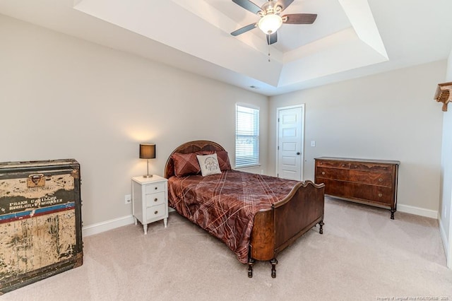 bedroom featuring light carpet, ceiling fan, and a tray ceiling